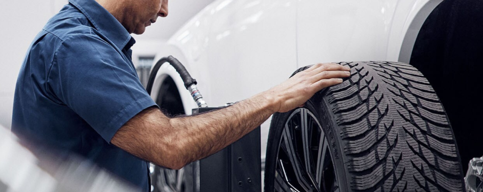 Técnico especializado Volvo revisando el neumático de un auto.