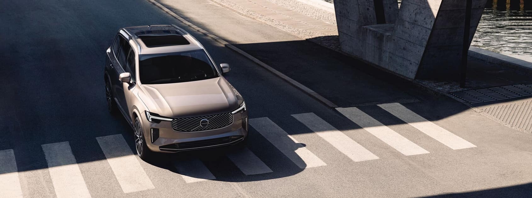 SUV de lujo hibrida Volvo XC90 color beige siendo conducida por calles de la ciudad.  